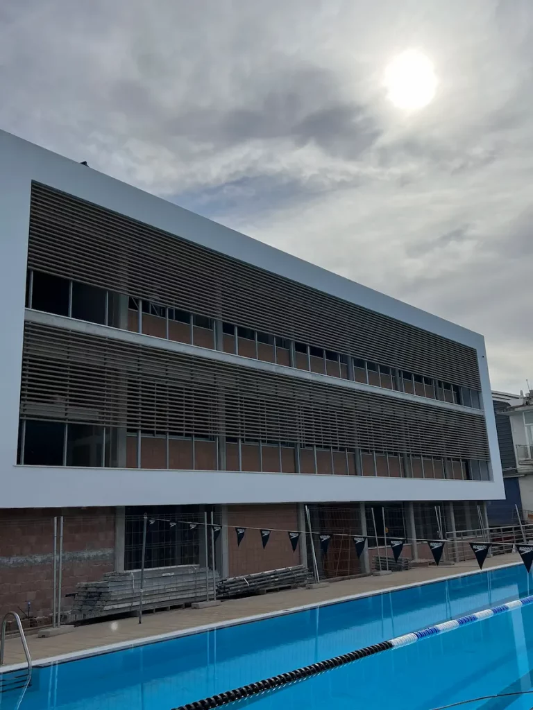 Módulo de aluminio con cuatro montantes verticales y perfiles horizontales en cerramiento del complejo deportivo