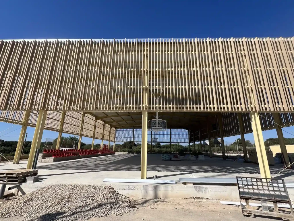 Sistema de protección solar con tubos de madera tecnológica en la cubierta de la pista de baloncesto por Novaltec