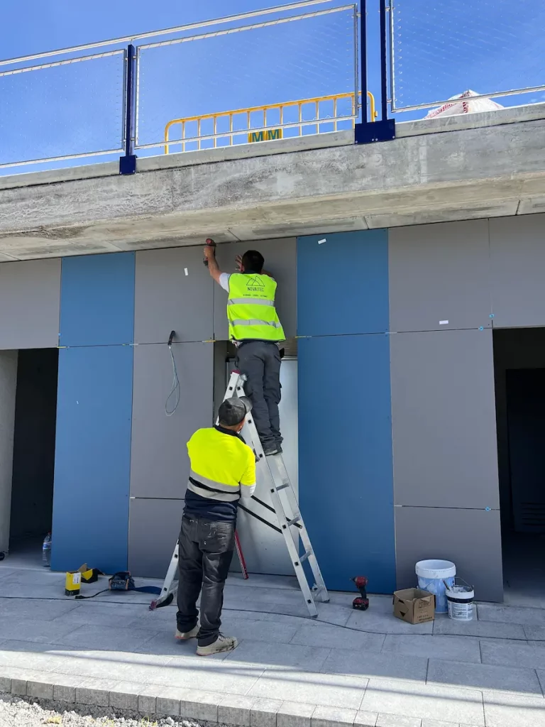 Operarios de Novaltec montando paneles de fachada en la planta baja de un edificio portuario