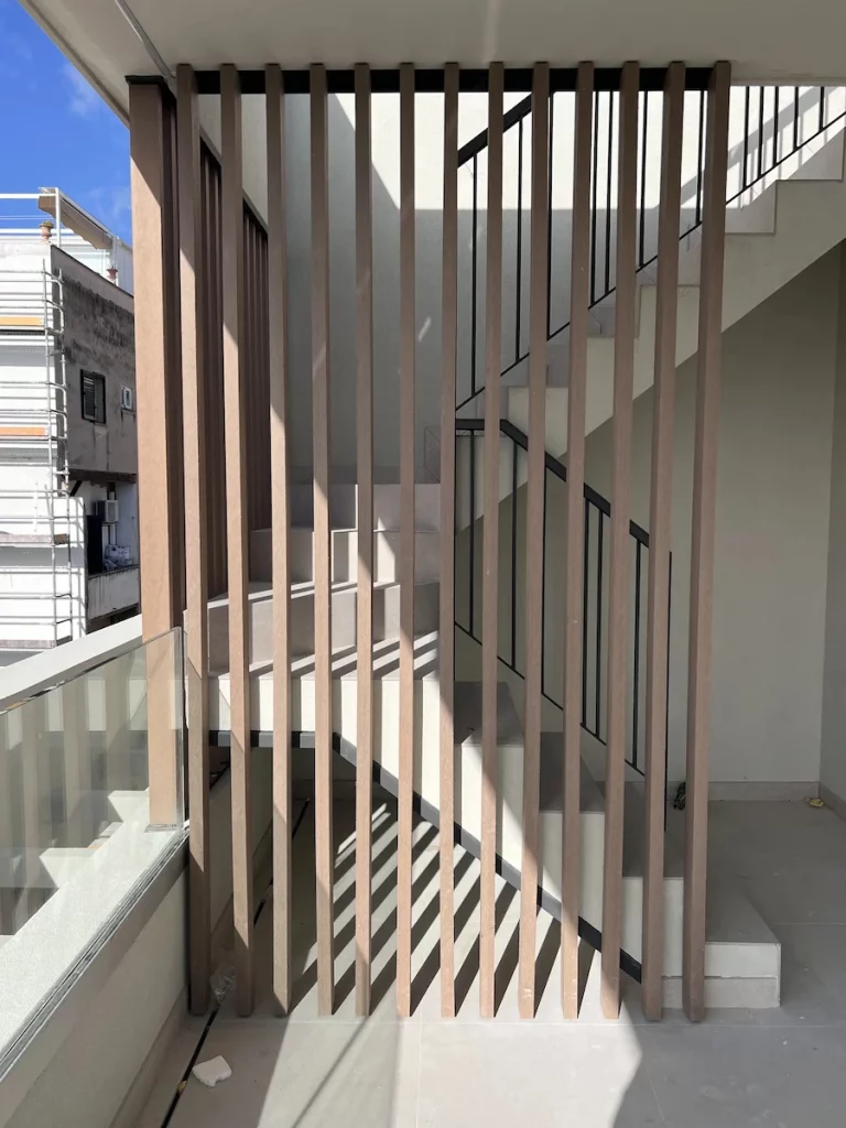 Estética cálida y contemporánea con madera tecnológica en balaustradas y fachada de vivienda
